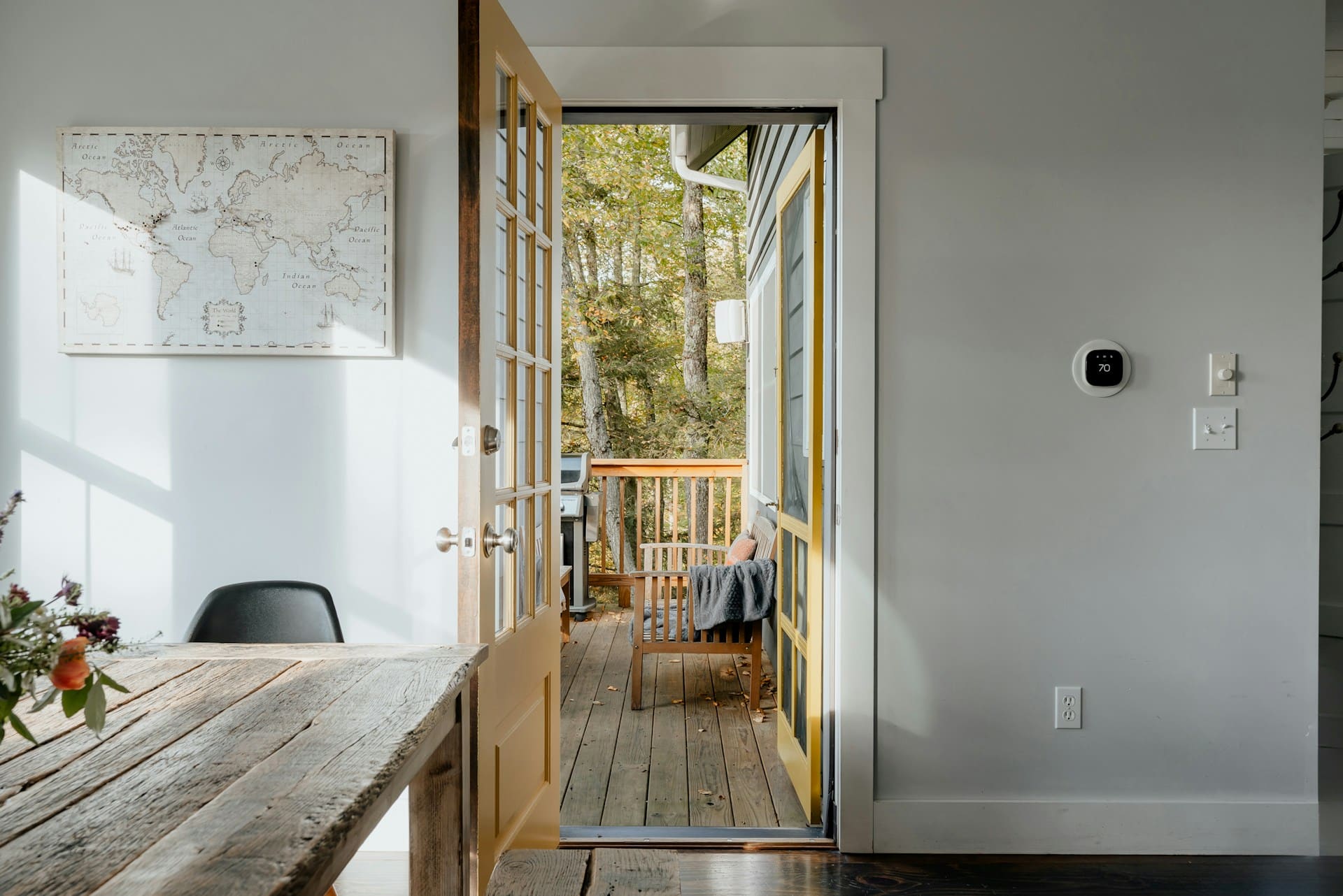 Open wooden exterior door with glass panels leading to a backyard deck, showing the door frame and hinges.